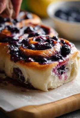 Freshly baked sourdough discard lemon blueberry rolls on a cooling rack