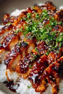 Plate of delicious Teriyaki Chicken garnished with green onions and sesame seeds.