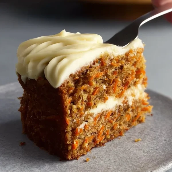 Slice of easy carrot cake with cream cheese frosting on a plate.
