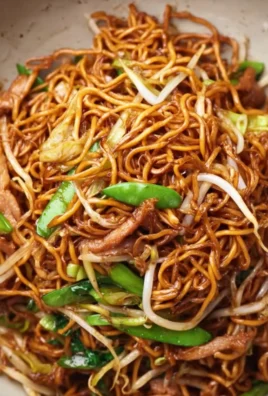Delicious soy sauce pan fried noodles garnished with vegetables and herbs.