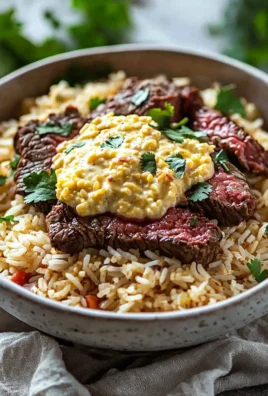 Plate of Steak Cheese Rice topped with melted cheese and garnished with herbs