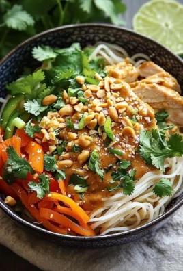 Delicious Thai peanut chicken noodle bowl topped with fresh herbs and veggies