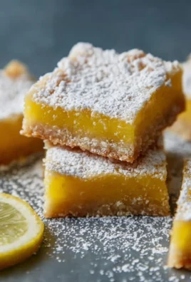 Delicious homemade lemon bars on a white plate with a dusting of powdered sugar