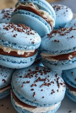Blue macarons filled with chocolate ganache on a decorative plate.