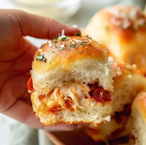 Homemade Hawaiian Roll Pizza Sliders served on a plate with pineapple and ham toppings.