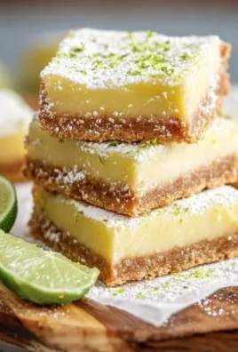 Key Lime Pie Bars on a plate with a lime wedge and graham cracker crust