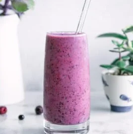 Smoothie aux baies, banane et trois baies dans un verre frais.