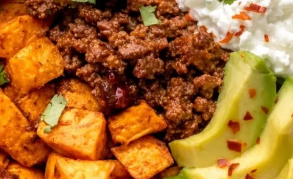 Colorful sweet potato taco bowl topped with fresh vegetables and spices