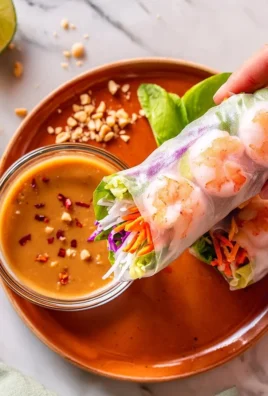 Vietnamese shrimp salad rolls served with creamy peanut sauce on a plate.